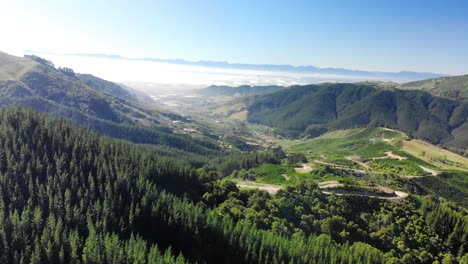 Aerial-landscape-view-of-Takaka-hill-valley,-with-a-winding-road-through-lush-vegetation,-New-Zealand