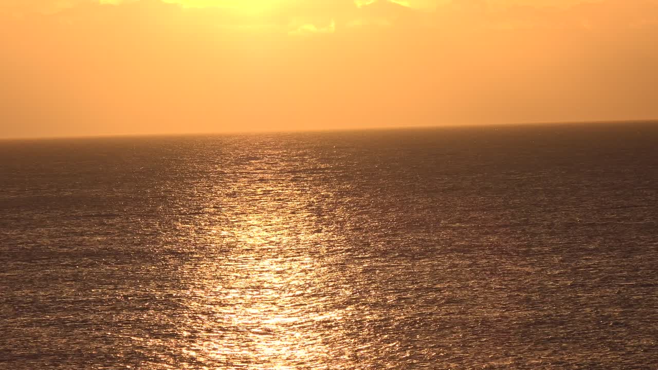 배경에 밝은 주황색 하늘이 있는 부드러운 주황색으로 바다 표면에 반사되는 일몰