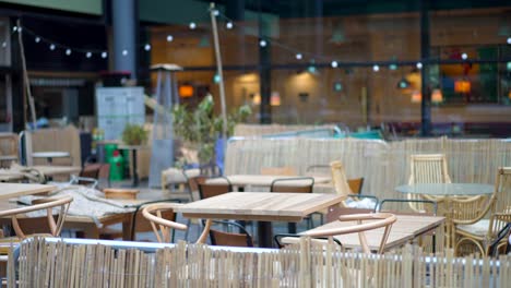 empty terrace of a restaurant or bar, empty wooden tables and seats during covid-19 coronavirus pandemic, no people during lockdown