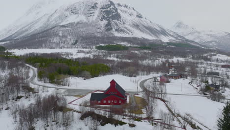 kaafjord church at the foot of a snow-capped mountain in the middle of winter in olderdalen norway - orbiting aerial shot