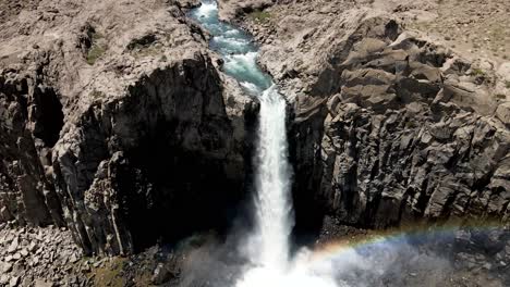 Vista-Aérea-De-Una-Toma-De-Grúa-De-Una-Poderosa-Cascada-Que-Genera-Un-Arco-Iris-Al-Caer-Por-La-Acción-De-Su-Poder