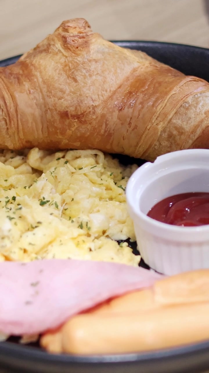 Croissant, uova strapazzate e prosciutto su un piatto