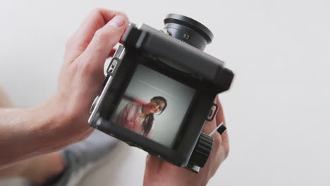 fotógrafo mirando en el visor de una cámara de formato medio de época tomando el retrato de una mujer joven