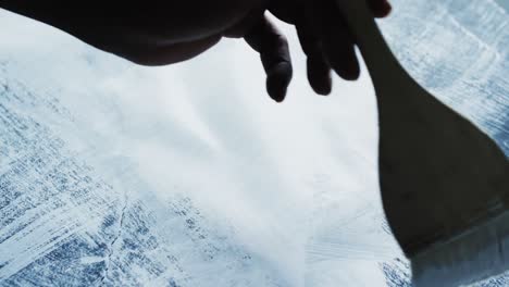 Hand-holding-brush-and-painting-stripes-with-white-paint-on-black-background,-slow-motion