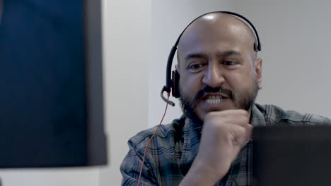 an asian man focused on his computer screen as he anxiously talks to himself in anticipation of the announcement of results, good news is received and he gestures with a fist pump in victory