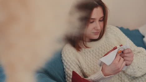 a red haired young woman cross stitching