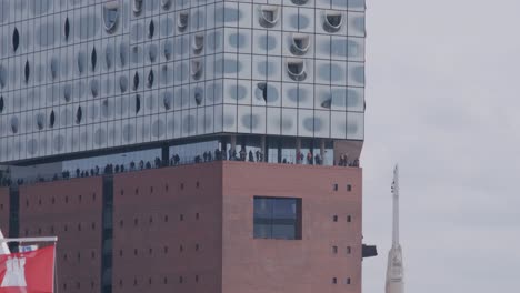 los visitantes de la elbphilharmonie disfrutan de la vista desde la terraza, el horizonte de hamburgo, día nublado