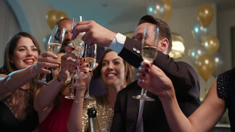 friends holding up champagne flutes together in a toast at party