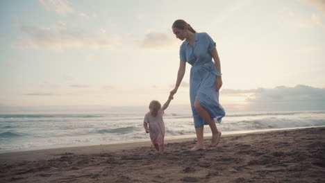 family walking by ocean on sunset