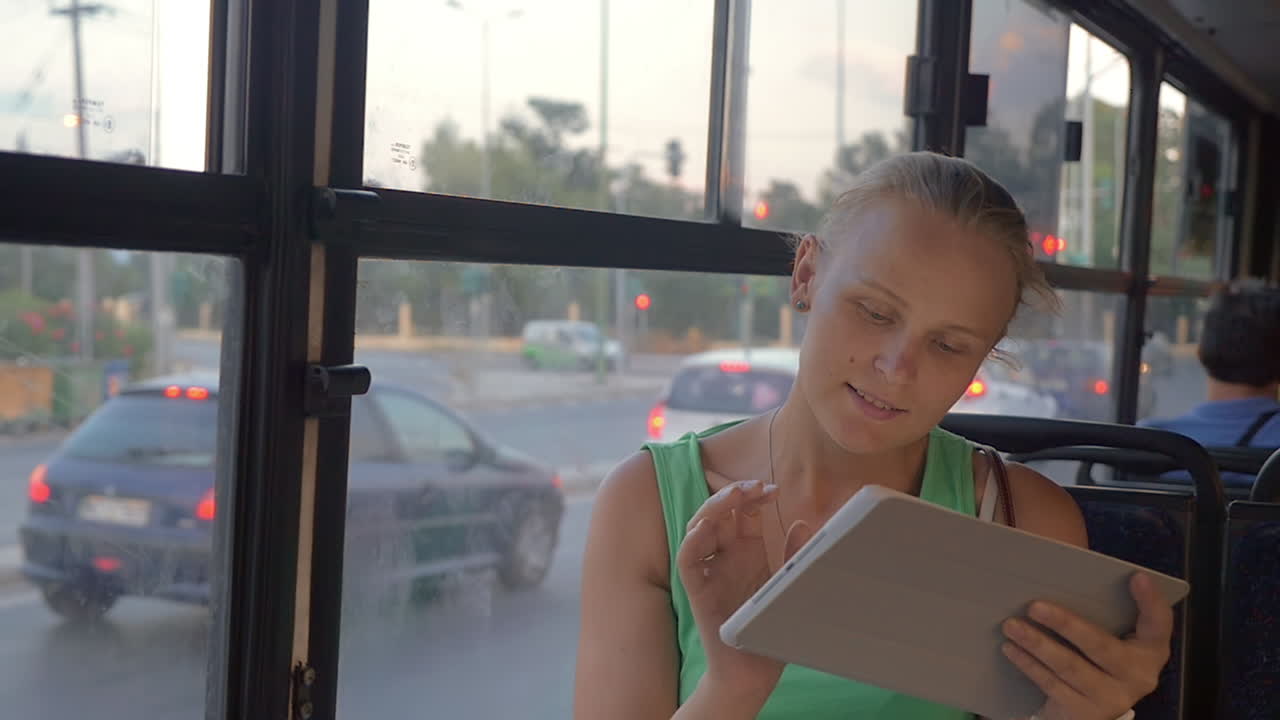 una mujer joven con un pad táctil viajando en autobús