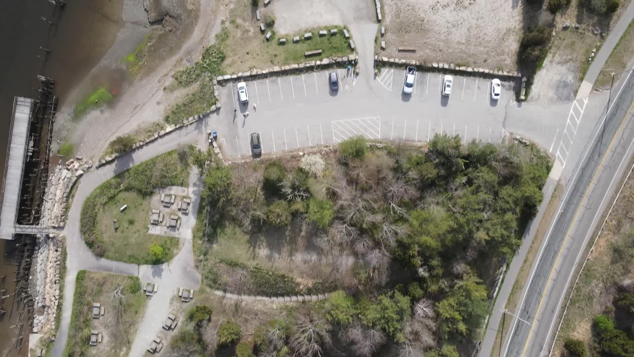 полет беспилотника с высоты птичьего полета над пригородным прибрежным парком с лодочным спуском, столиками и приливными водно-болотными угодьями