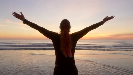 woman-spreads-her-arms-and-breathes-watching-the-sunrise
