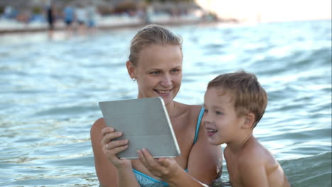 Mother-with-pad-shows-his-son-photo-or-video-in-water