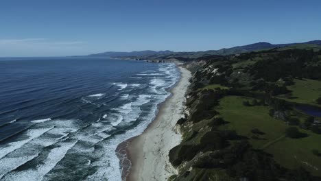 aerial shot of beautiful northern california coastline with ocean waves and green mountains