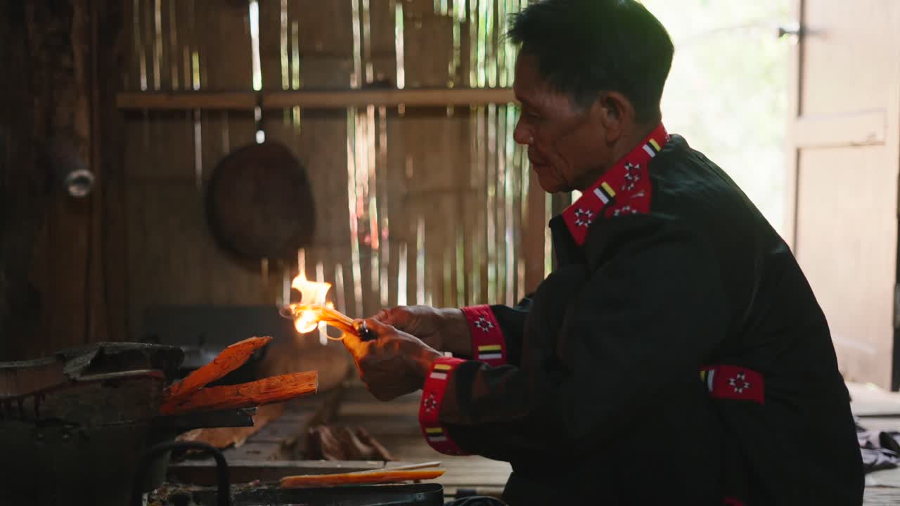 Man tending to a fire in a traditional setting