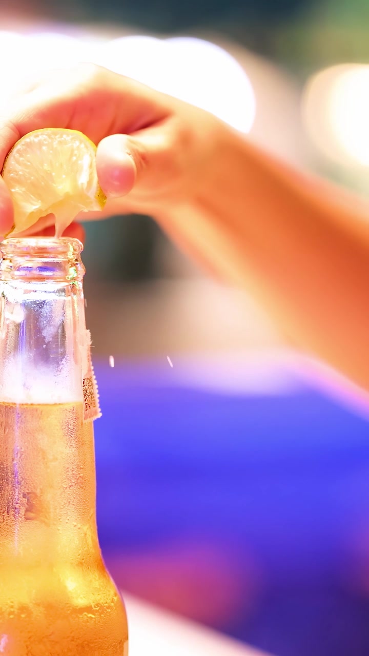 Mano che spreme limone in una bottiglia di birra