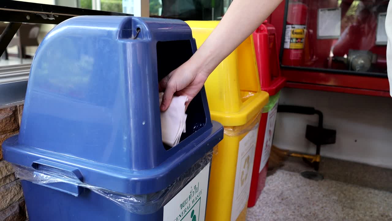 Person throwing waste into segregated recycling containers.