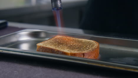 el cocinero tostando una rebanada de pan usando un quemador de gas