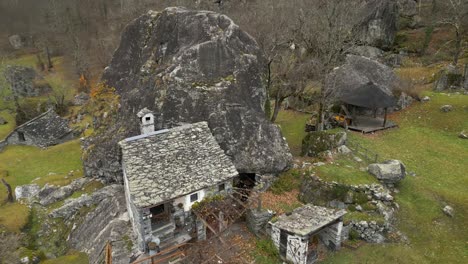 Aerial-drone-rotating-shot-over-ruins-of-old-stone-walled-houses-in-Cavergno-village,-District-of-Vallemaggia,-Canton-of-Ticino,-Switzerland-on-a-cloudy-day