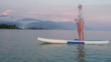 una mujer haciendo paddleboard al atardecer.