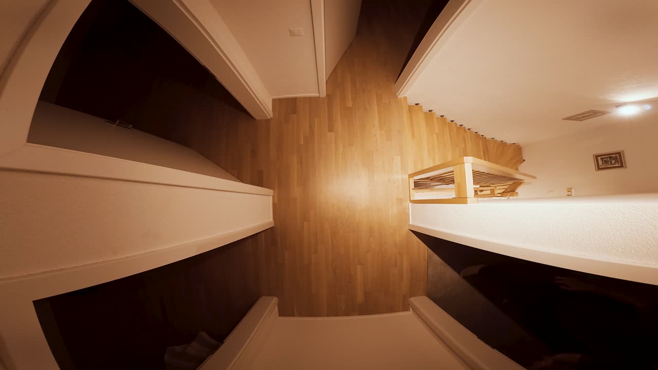 A man walks nervously from room to room, as if lost or searching for someone, filmed from an overhead view