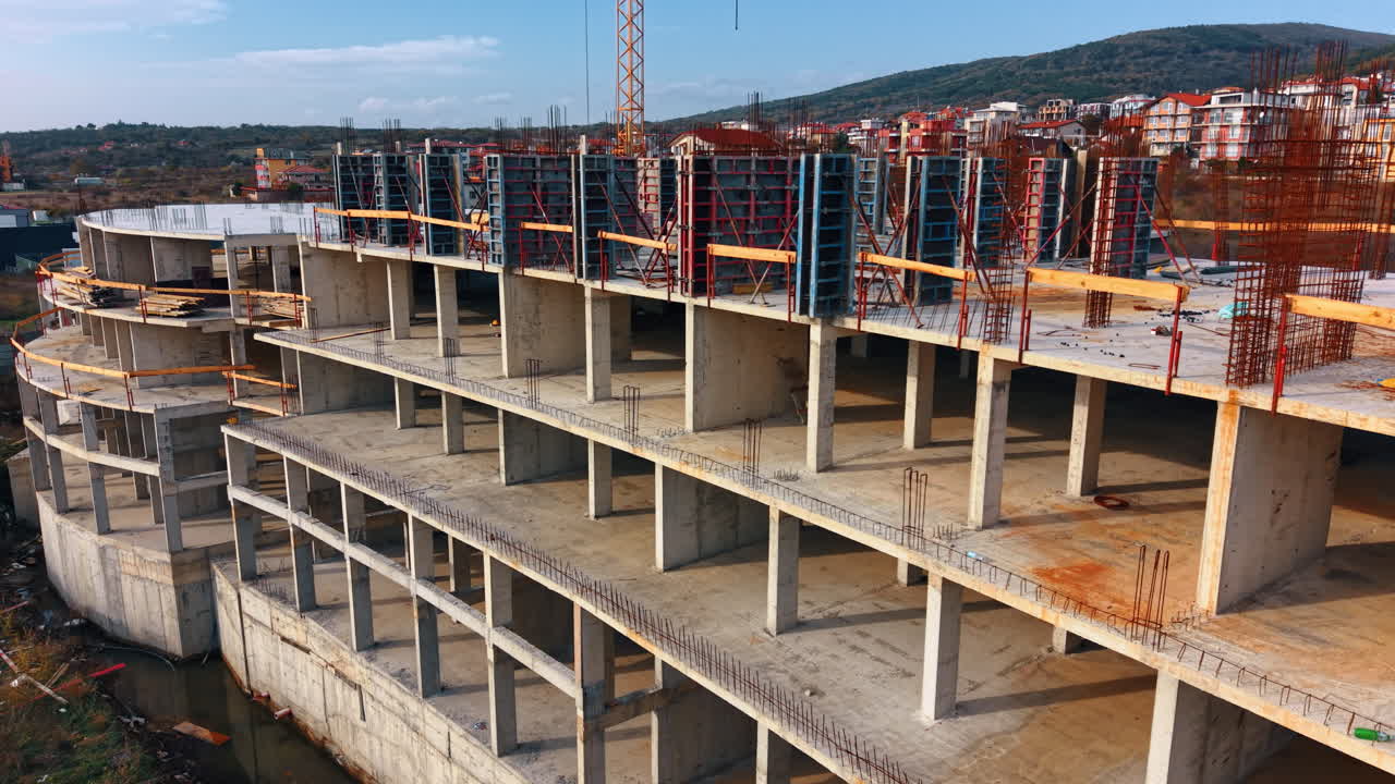 Concrete building frame under construction with steel rebar. Aerial view of a multi-story concrete building structure with exposed rebar and formwork on a construction site