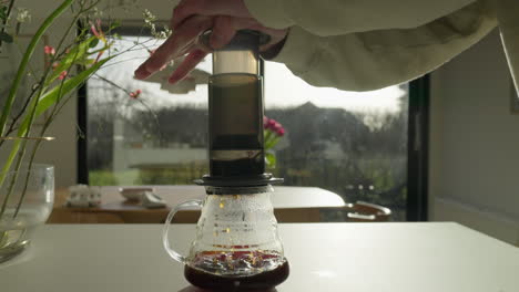 presionando una cafetera en una mesa de cocina soleada