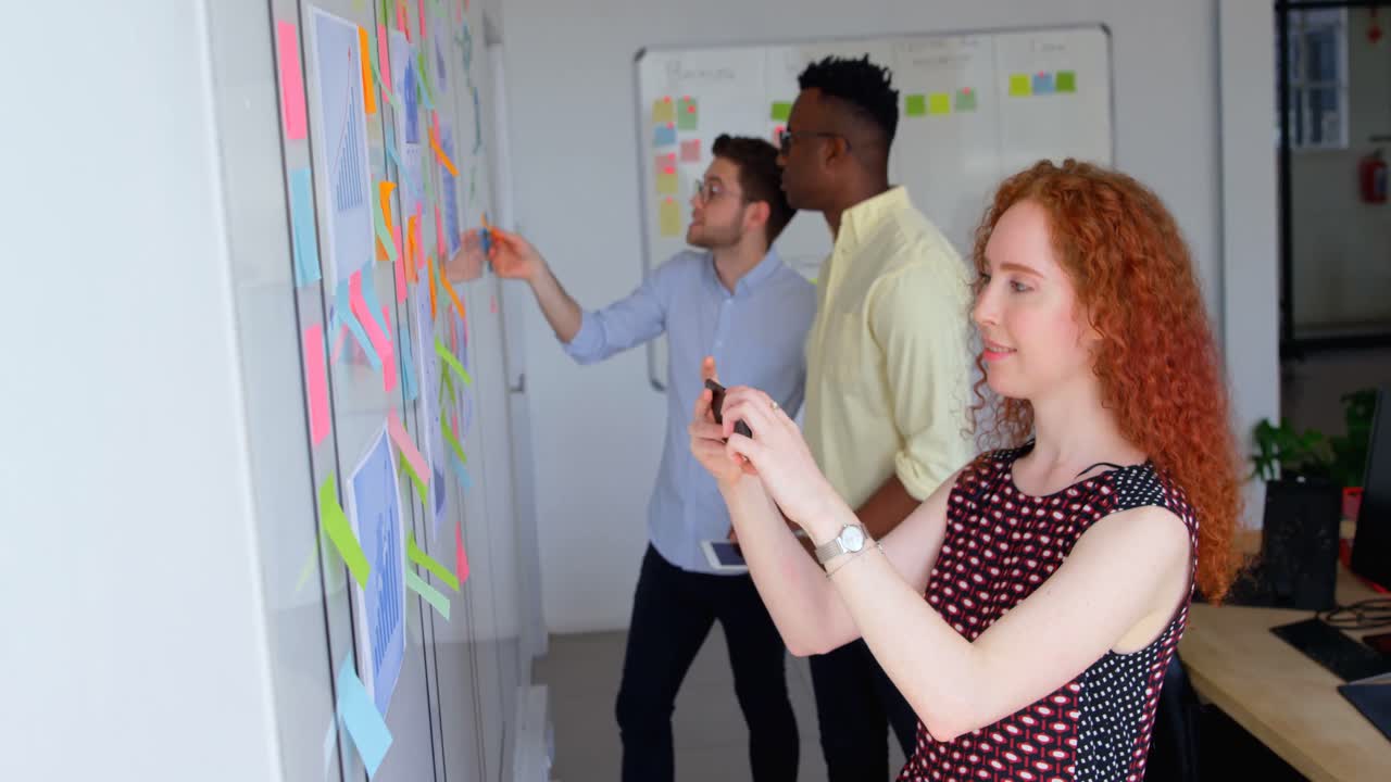 vista lateral de una joven mujer de negocios caucásica haciendo clic en la foto de la pared de vidrio con un teléfono móvil 4k