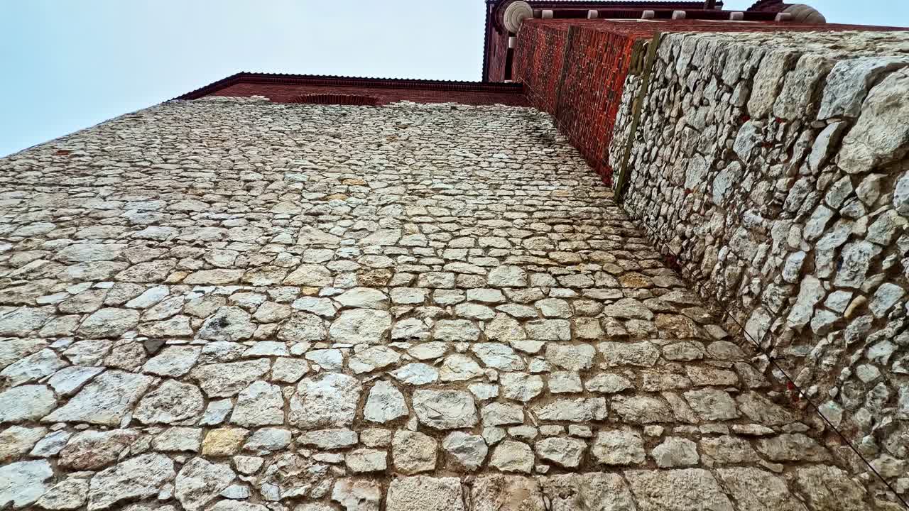 Vista dal basso di una parete in pietra e mattoni sulla torre del Castello Reale di Wawel a Cracovia