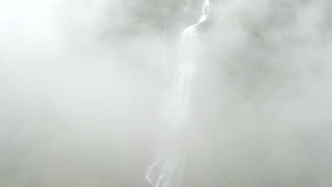 shoot of waterfall in norway. drone increasing altitude rising in clouds. majestic dreamy look.