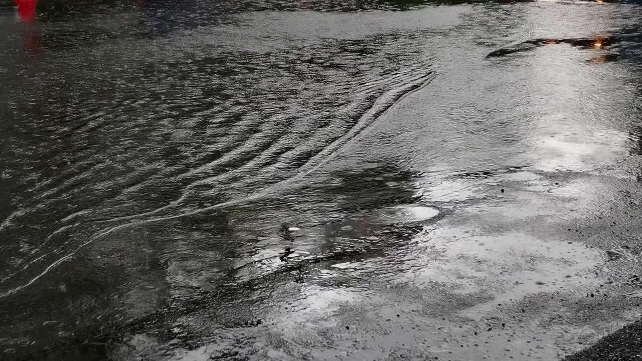 Close-Up View Captures the Graceful Ripples and Patterns Crafted by Falling Rain on the Road
