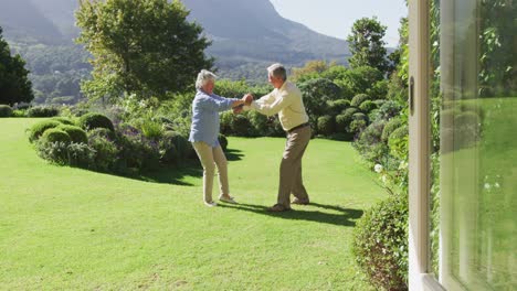 Feliz-Pareja-De-Ancianos-Caucásicos-Bailando-Juntos-En-El-Jardín-En-Un-Día-Soleado