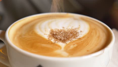 close up of a cappuccino with latte art and sugar sprinkled on top