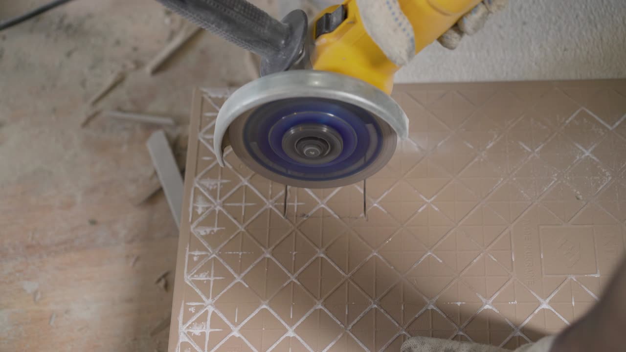 trabajador cortando una baldosa usando una molienda angular en el sitio de construcción. un trabajador está cortando baldosas.