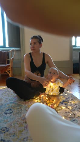 mom and baby play with christmas lights