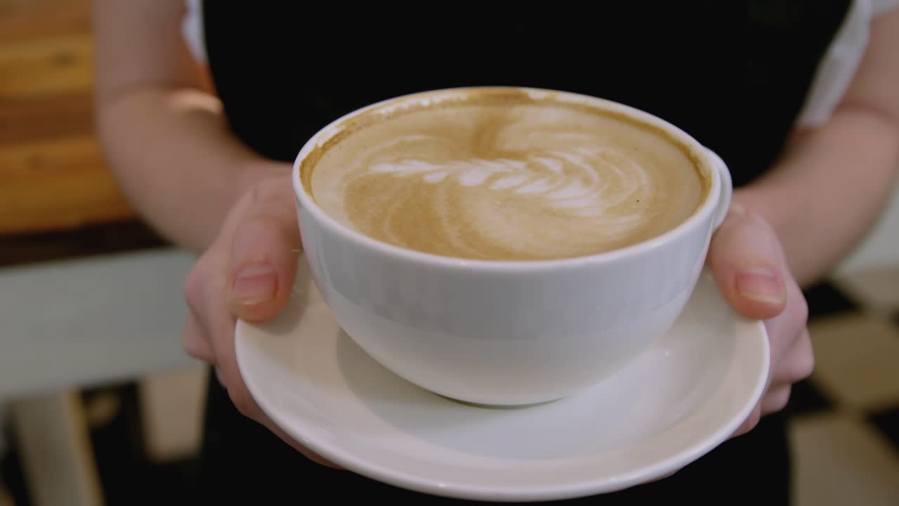 Moving latte cup forward, barista causing finance charts to flow around rim illustrating trends