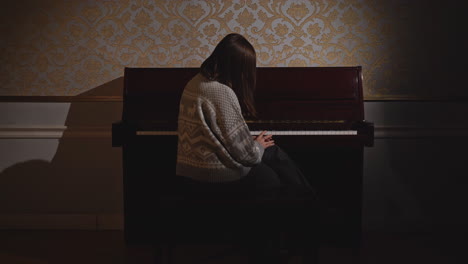 woman playing piano in a dark room