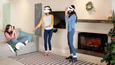 women friends enjoying virtual reality gaming by fireplace during christmas celebration