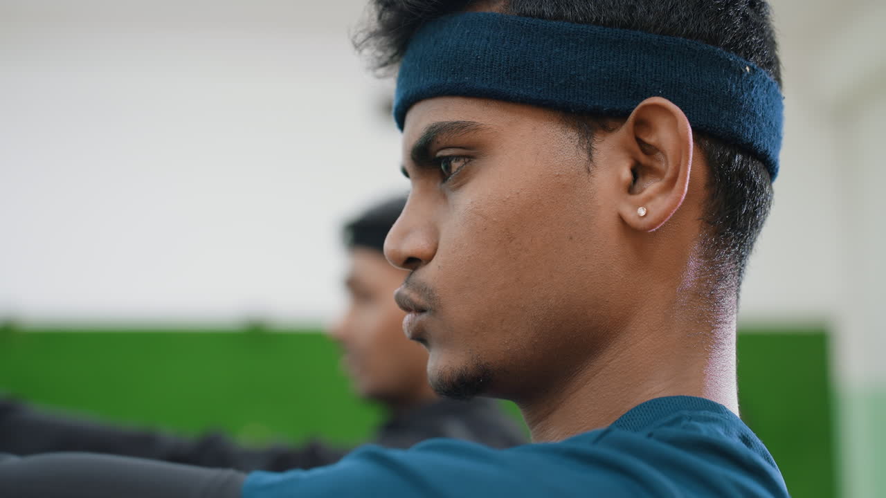 Close up of teammates exercising during indoor workout session showing determination, focus, and teamwork with blurred training partner in background