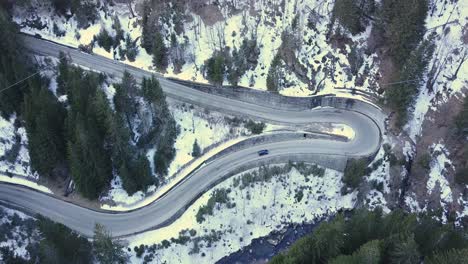 drone aerial view of a car going up a snowy mountain road in winter