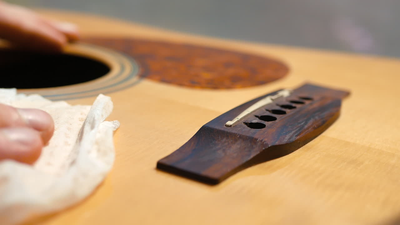 Premium stock video - Musician cleaning and oiling an acoustic guitar