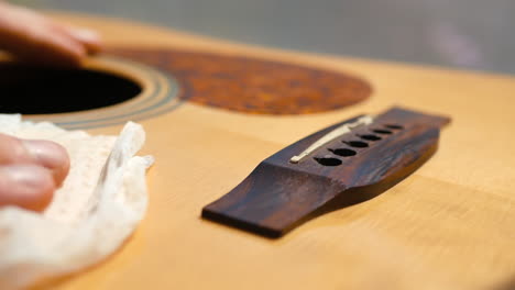 musician cleaning and oiling an acoustic guitar neck and body