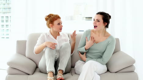 two attractive women fighting sitting on couch