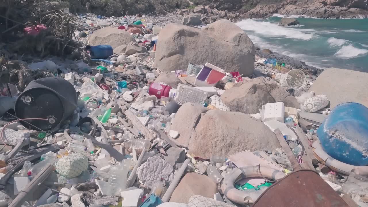 Environmental destruction caused by beach covered in plastic and rubbish causing climate change in Hong Kong. Aerial drone view