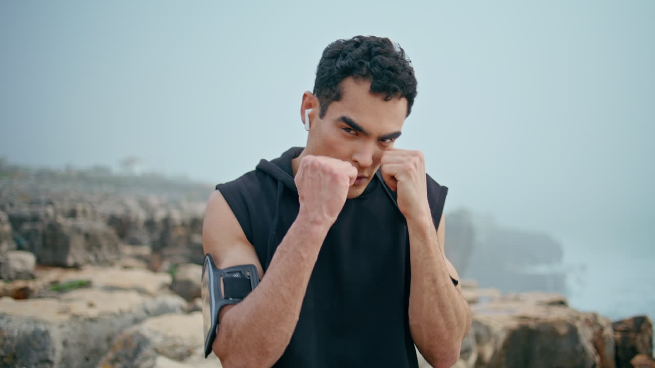 Professional athlete punching workout at seaside closeup. Strong boxer posing