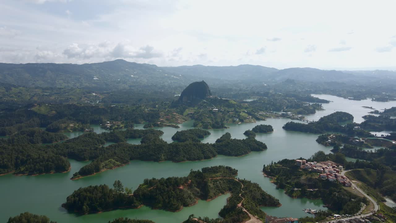 High angle aerial of Rock of Guatape overlooking lake, emphasizing vibrant landscapes and unique tropical geography and homes built in highlands surrounding regions