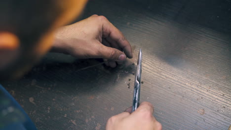 jeweler cuts parts from golden spiral at table close view