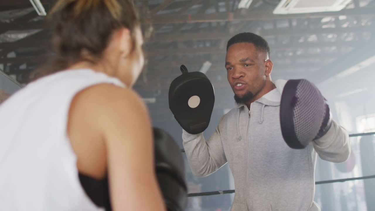 Coach raising mitts, trainee throwing punches in boxing training for skill, blue overlays obscuring