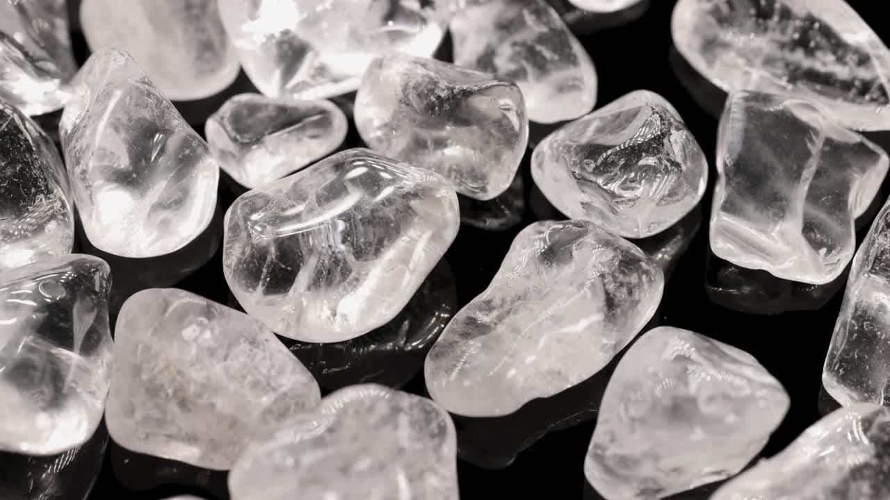 Clear quartz stones displayed on a black surface with bright lighting, highlighting their transparency and texture