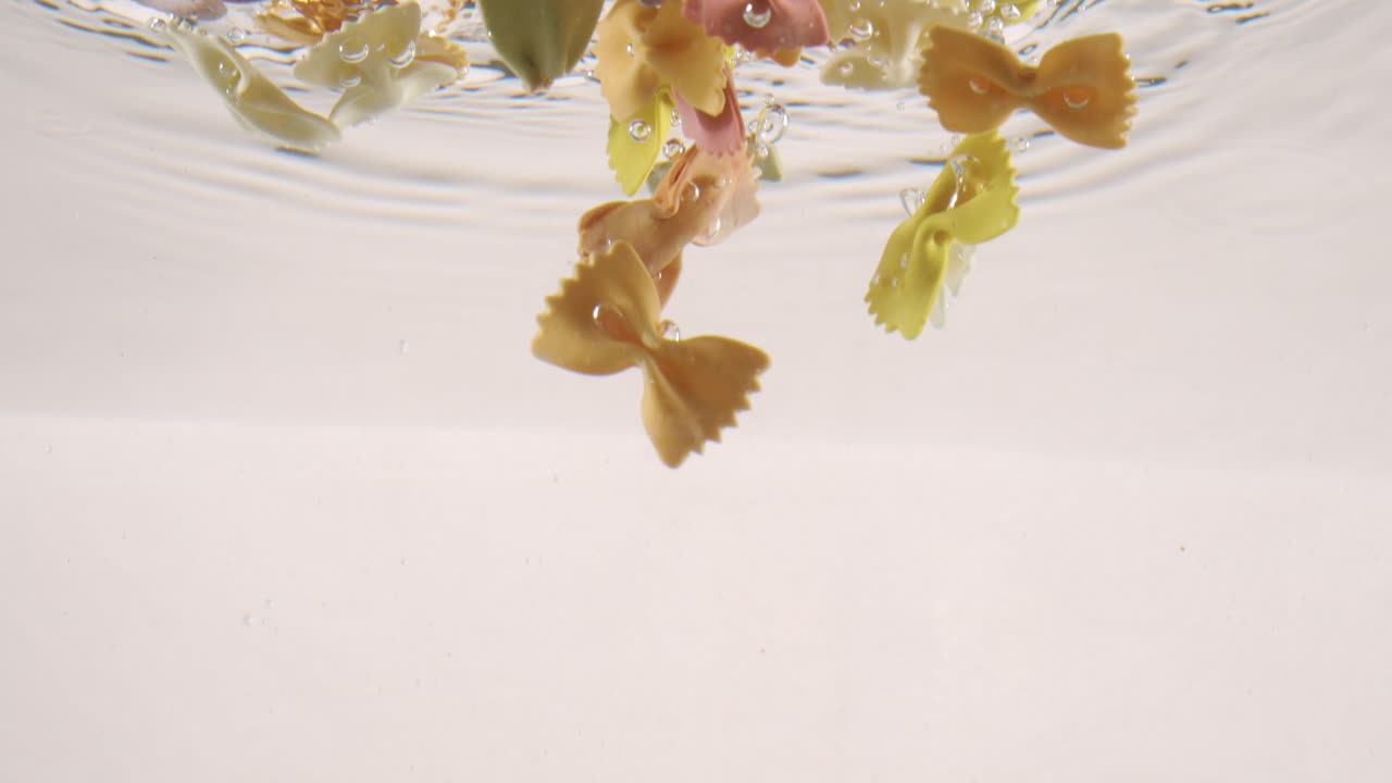 farfalle pasta tricolore en agua hirviendo. filmado con una cámara súper lenta de 1000 fps.